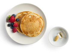 A plate with 2 pancakes and fruit, prepared with Optavia Ascend Waffle and Pancake Mix.